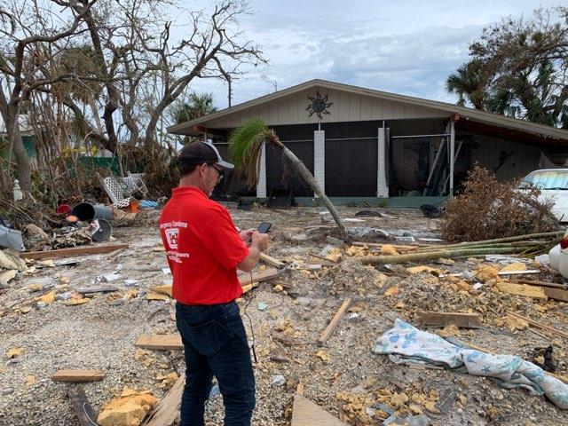 white male checking the damage to a house by a hurricane